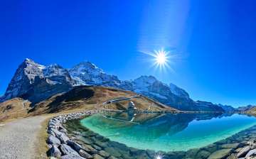 Le lac Fallbodensee, près de la Petite Scheidegg, baigne sous un ciel radieux. En arrière-plan se dressent l'Eiger, le Mönch et la Jungfrau.