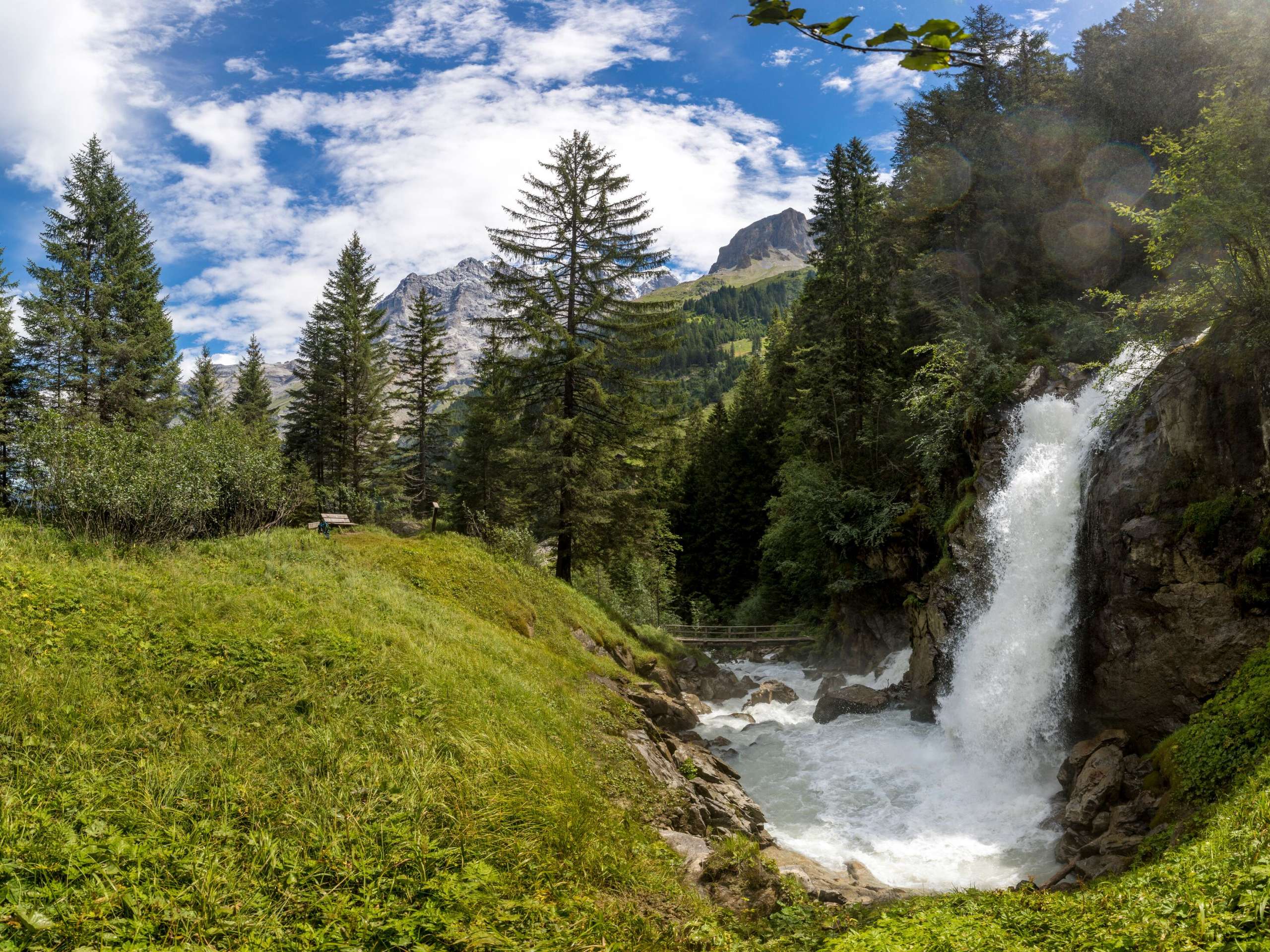 A small waterfall with lots of water feeds the mountain stream in the Lauterbrunnen valley.