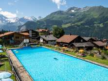 Schwimmbecken und Café in mitten des Dorfes Wengen, mit umliegenden Panorama des Lauterbrunnentals.