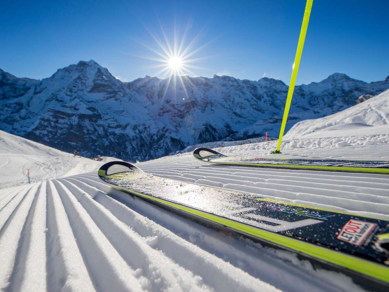 Skier posieren auf der Piste in Mürren-Schilthorn. Das Dreigestirn Eiger, Mönch und Jungfrau ist aus der Ferne zu sehen.