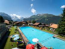 Schwimmbecken und Café in mitten des Dorfes Wengen, mit umliegenden Panorama des Lauterbrunnentals.