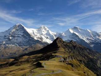 Vue sur le Männlichen en été, avec en arrière-plan le « Dreigestirn » (le trio) enneigé composé de l'Eiger, du Mönch et de la Jungfrau.