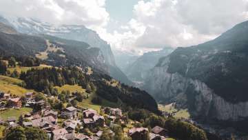 Aussicht mit dem Dorf Wengen ins Lauterbrunnental im Sommer. Der Himmel ist leicht bewölkt.