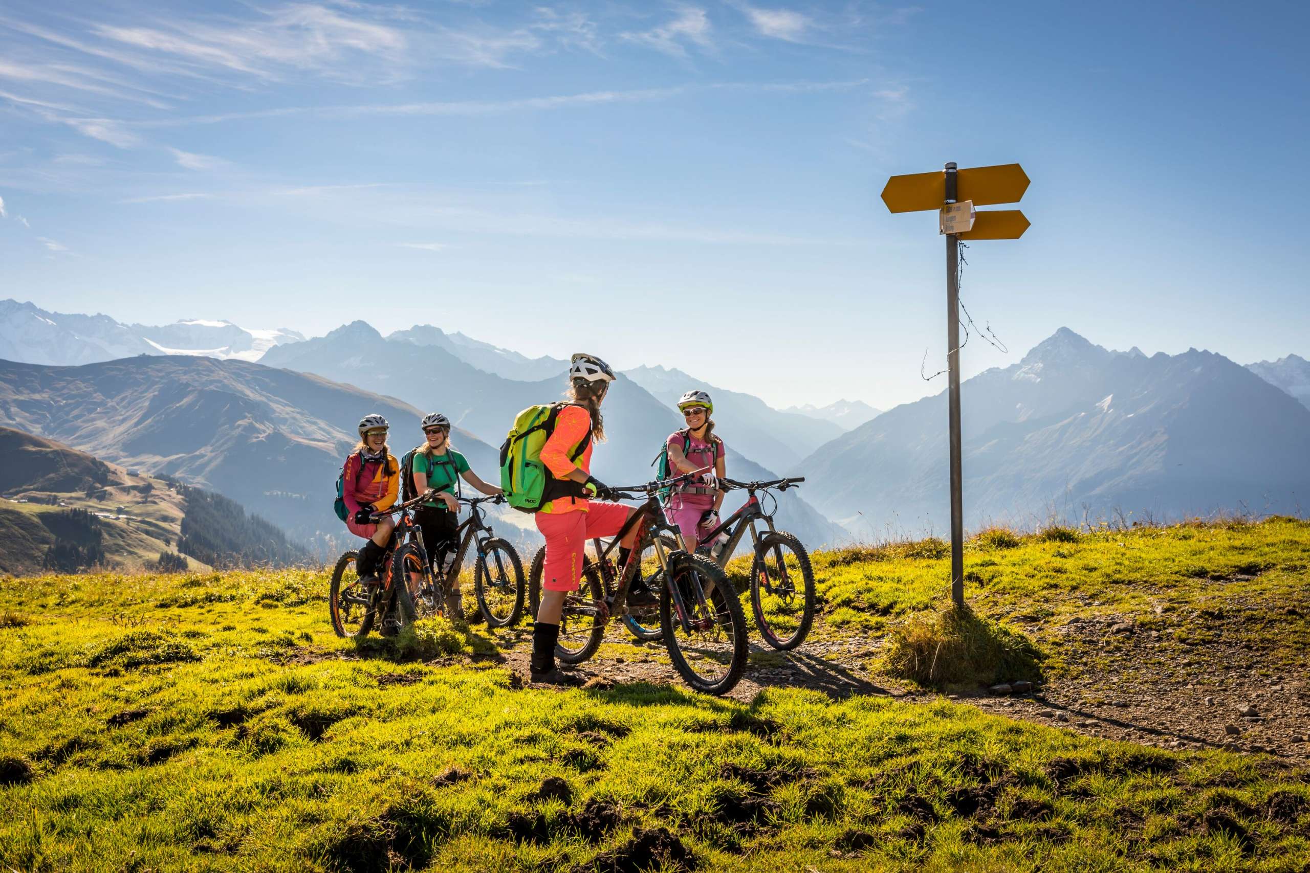 The bikers look at the signpost and enjoy the view from the Hasliberg. The view offers a summery vista over the mountain landscape.