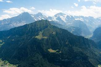 Sicht auf den grünen Männlichen und im Hintergrund auf das sommerliche Dreigestirn Eiger, Mönch und Jungfrau