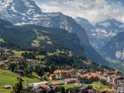 Hinter dem sommerlichen Dorf Wengen sieht man das Lauterbrunnental mit den steilen Felsen.