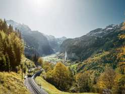 The Wengernalpbahn on its way from Lauterbrunnen to Wengen. In the background, the Lauterbrunnen Valley, bathed in autumn colors, with the Staubbach Falls.