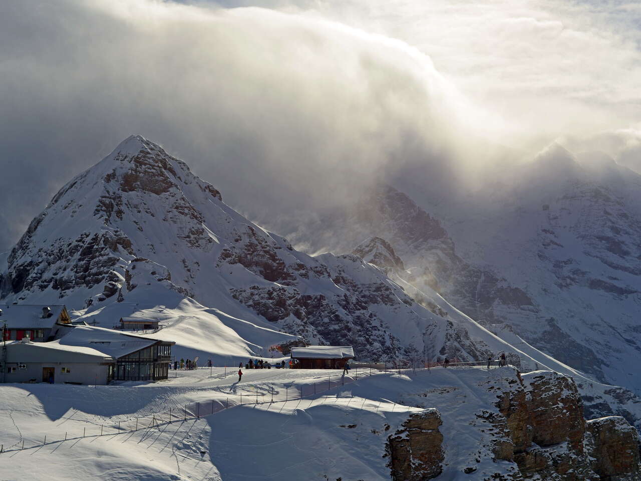 A change in the weather on the snow-covered Männlichen. The sun is able to push through the clouds in places.