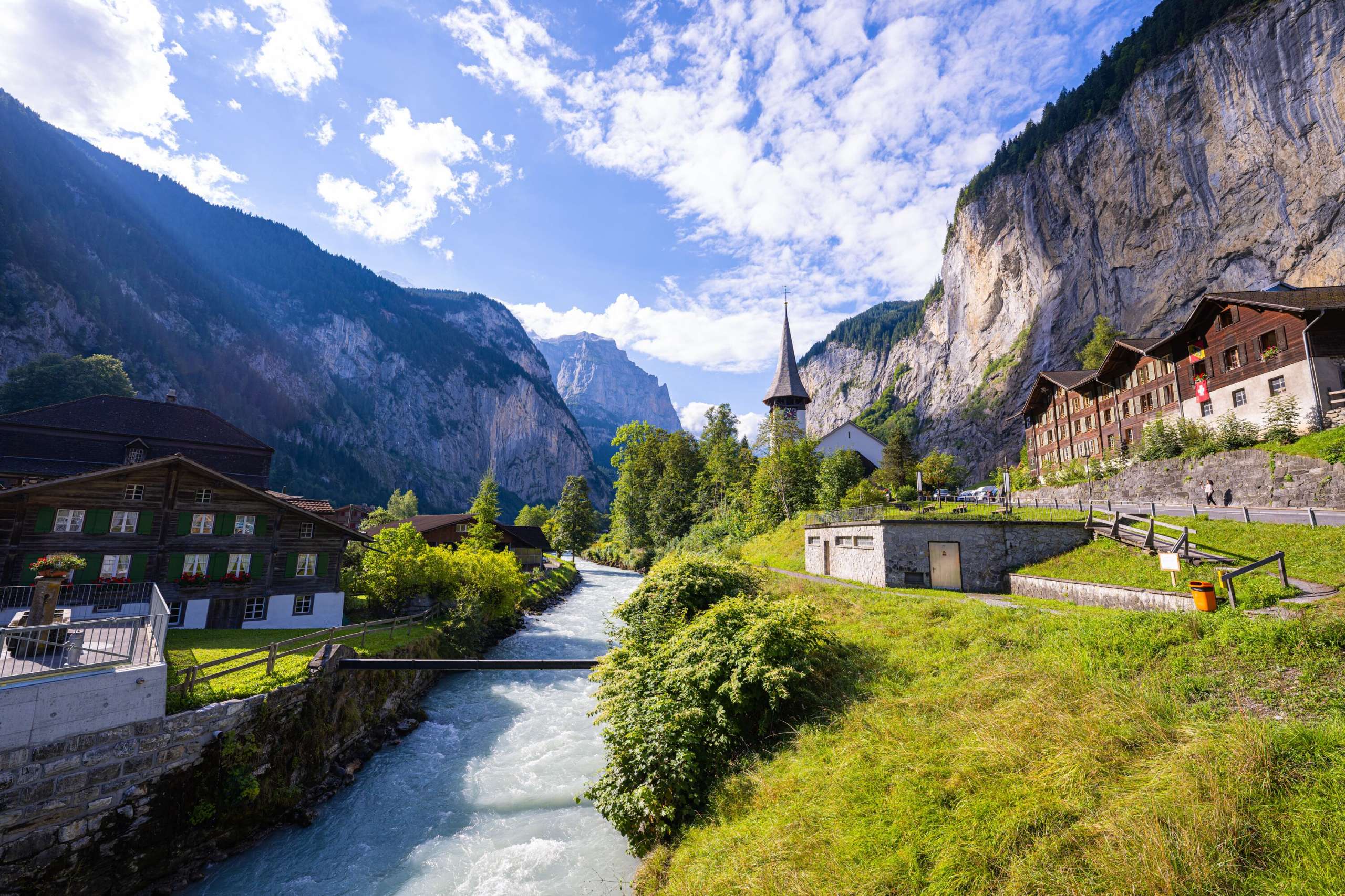 Die Lütschine fliesst durch das Dorf Lauterbrunnen. Die Kirche steht neben dem Fluss und zwischen steilen Felsen des Lauterbrunnentals.