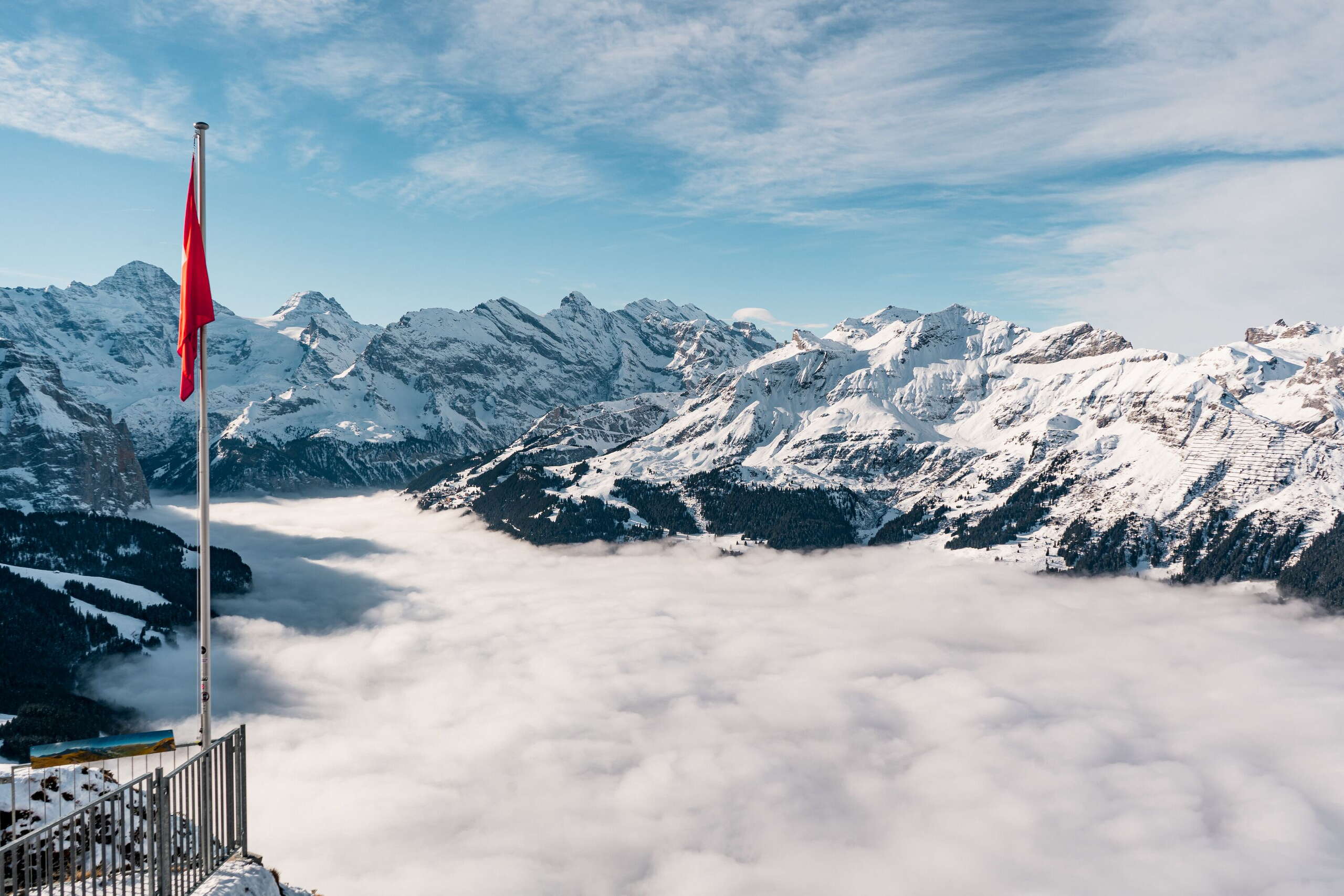 Aussicht vom Männlichen über das Nebelmeer im Lauterbrunnental. Im Hintergrund ist das verschneite Bergpanorama zu sehen.