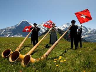 Lors de la fête du printemps à la montagne, au Männlichen, trois musiciennes et musiciens jouent du cor des Alpes dans la prairie.