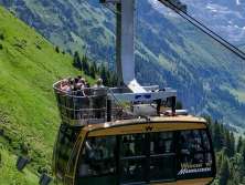 Le téléphérique Wengen–Männlichen monte en survolant des prairies alpines escarpées. En arrière-plan, l'impressionnant paysage de haute montagne se détache, soulignant l'emplacement spectaculaire de la ligne.